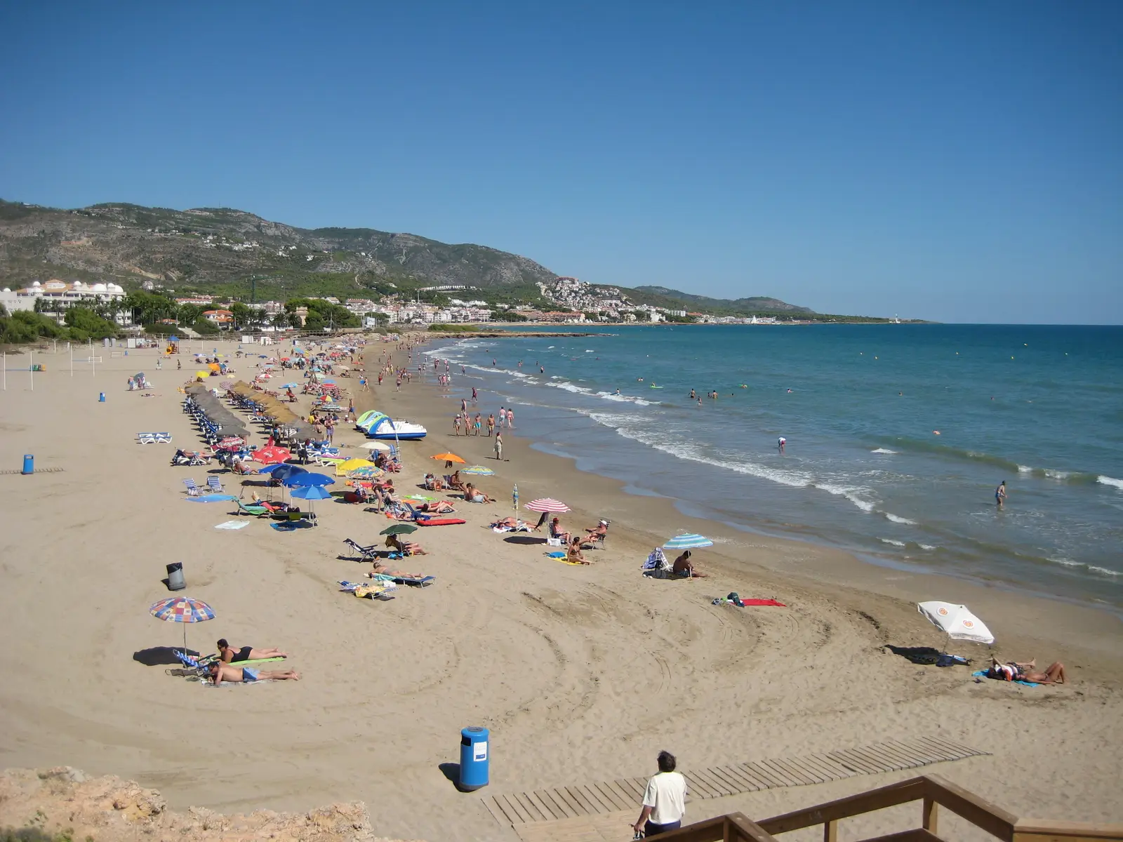 Strand Romana in Alcossebre mit Sonnenschirmen und den Bergen im Hintergrund